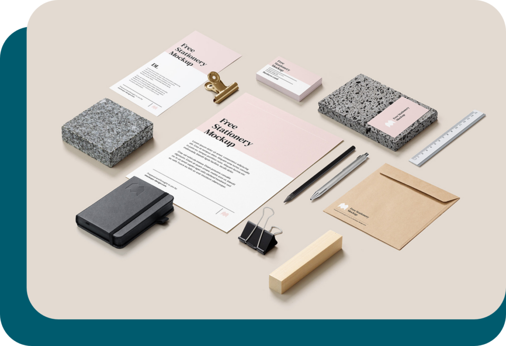 Différents types de supports de communication (carte de visite, flyer, plaquette, enveloppe personnalisée...) positionnés de manière harmonieuse avec un stylo, un crayon, un carnet, des pinces et une règle, sur un fond beige. Tous les supports sont harmonisés au niveau du graphisme.